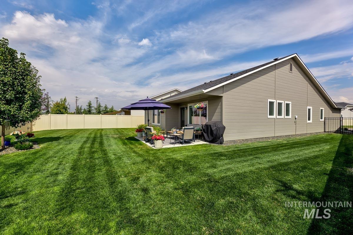 348 West Radiant Rdg Drive Meridian, ID 83642 - Photo 28 of 36 Expansive fenced backyard featuring a concrete patio, mature tree, and light-colored siding