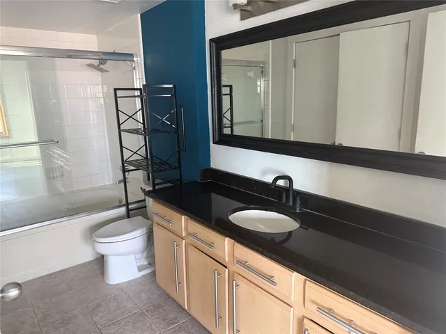 a bathroom with a granite countertop sink a toilet a mirror and shower