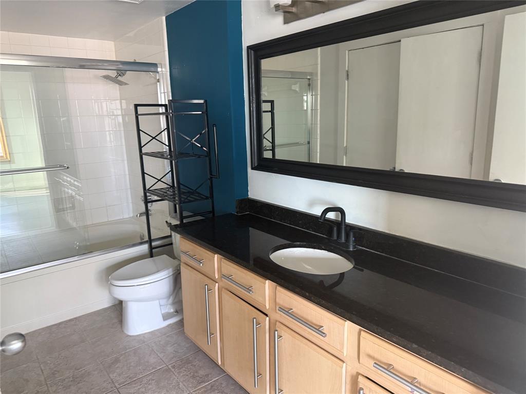 2502 Live Oak Street, Unit 228 Dallas, TX 75204 - Photo 14 of 21 a bathroom with a granite countertop sink a toilet a mirror and shower