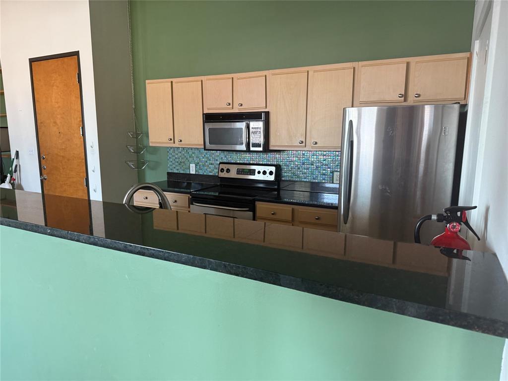 2502 Live Oak Street, Unit 228 Dallas, TX 75204 - Photo 5 of 21 a kitchen with kitchen island a counter top space cabinets and stainless steel appliances