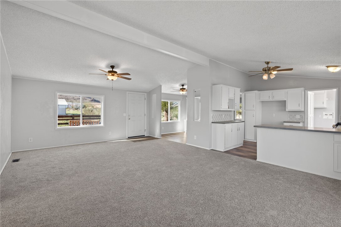 2294 South Dragoon Road Golden Valley, AZ 86413 - Photo 22 of 35 Unfurnished living room with dark colored carpet, a textured ceiling, and a ceiling fan