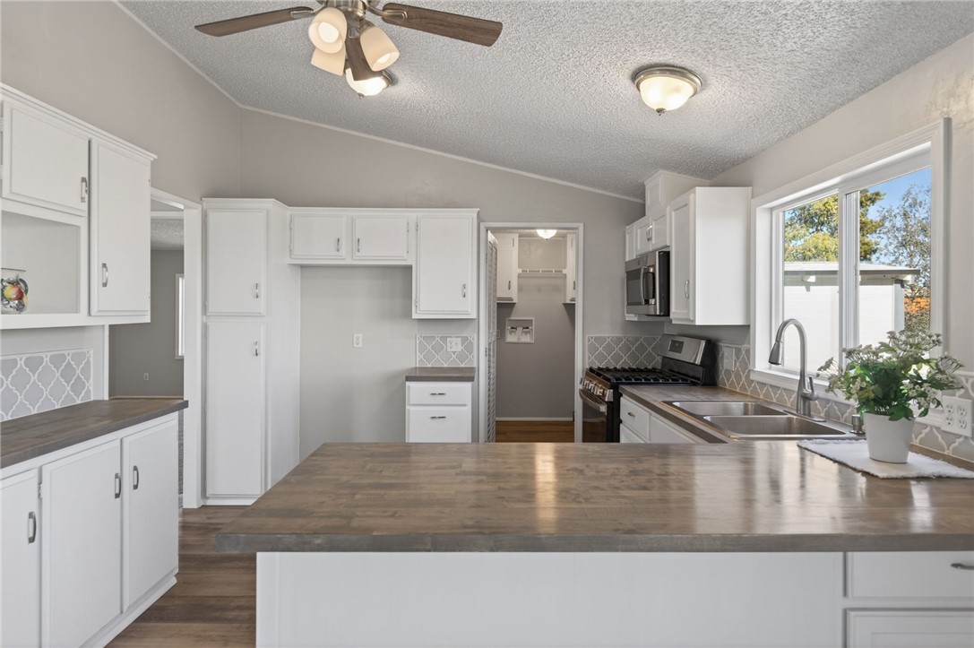2294 South Dragoon Road Golden Valley, AZ 86413 - Photo 23 of 35 Kitchen featuring white cabinets, backsplash, stainless steel appliances, vaulted ceiling, and a ceiling fan