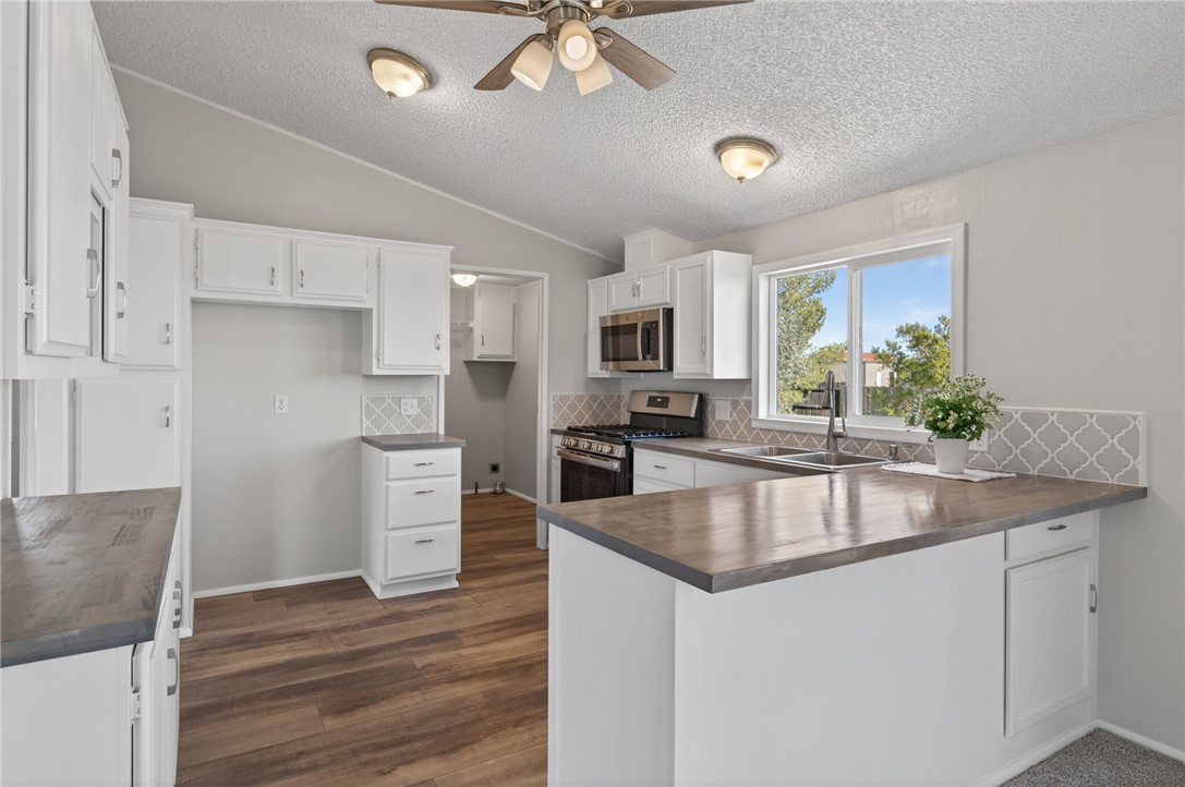 2294 South Dragoon Road Golden Valley, AZ 86413 - Photo 24 of 35 Kitchen with a peninsula, appliances with stainless steel finishes, white cabinetry, ceiling fan, and a textured ceiling