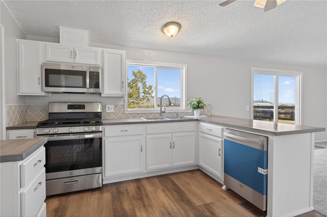 2294 South Dragoon Road Golden Valley, AZ 86413 - Photo 25 of 35 Kitchen with appliances with stainless steel finishes, white cabinets, a peninsula, and new flooring