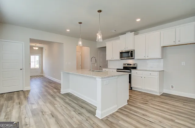 a kitchen with granite countertop a stove top oven a sink and white cabinets with wooden floor