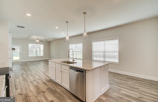a kitchen with stainless steel appliances granite countertop a sink a window and wooden floors