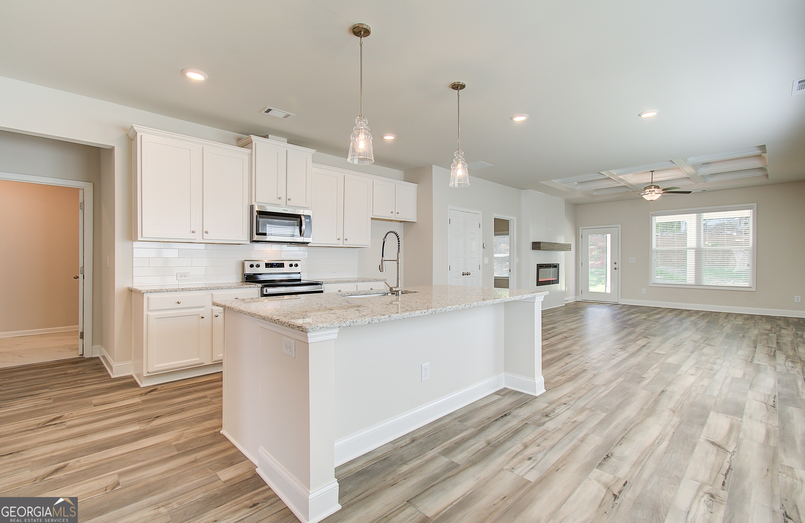 71 Avian Way, Unit 17B Auburn, GA 30011 - Photo 8 of 32 a kitchen with stainless steel appliances kitchen island granite countertop a stove a sink a refrigerator and white cabinets with wooden floor