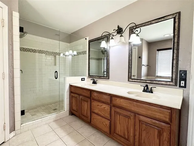 a bathroom with a double vanity sink mirror and shower
