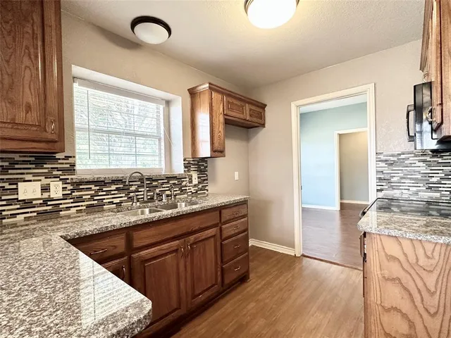 a kitchen with stainless steel appliances granite countertop a sink stove and wooden floor
