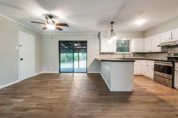 a large kitchen with kitchen island a stove a sink a center island and wooden floor