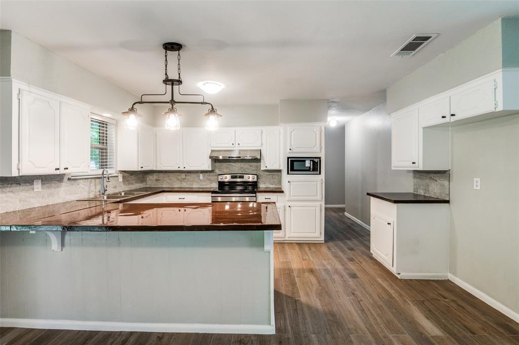1533 East Springcrest Circle Lancaster, TX 75134 - Photo 14 of 25 Kitchen featuring white cabinetry, wood-finish flooring, dark countertops, a tile backsplash, and a contemporary multi-bulb chandelier