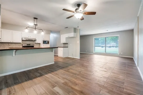 a view of a kitchen with a stove cabinets a ceiling fan and wooden floor