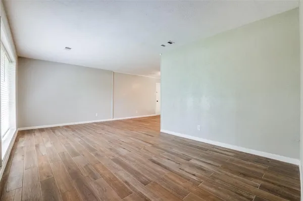 a view of an empty room with wooden floor