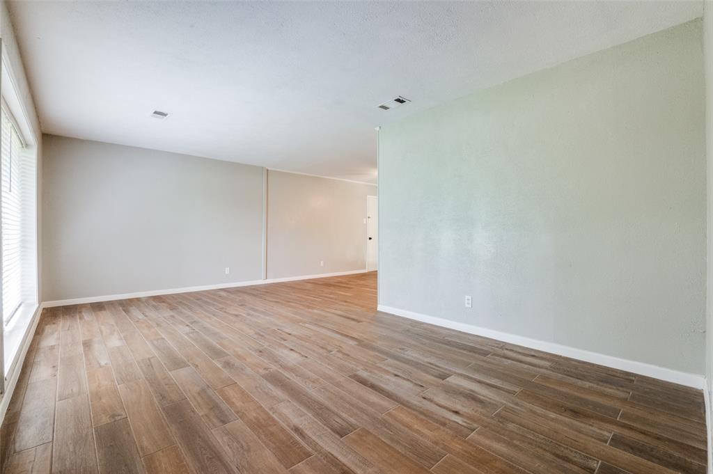 1533 East Springcrest Circle Lancaster, TX 75134 - Photo 16 of 25 Spacious interior room featuring wood-finish flooring, neutral wall tones, white baseboards, and ample natural light from a window with horizontal blinds