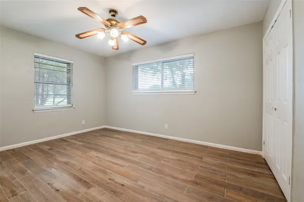 a view of an empty room with window and wooden floor
