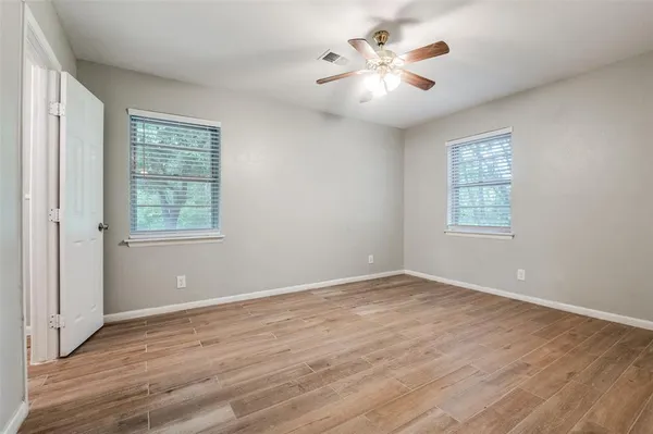 an empty room with wooden floor and window