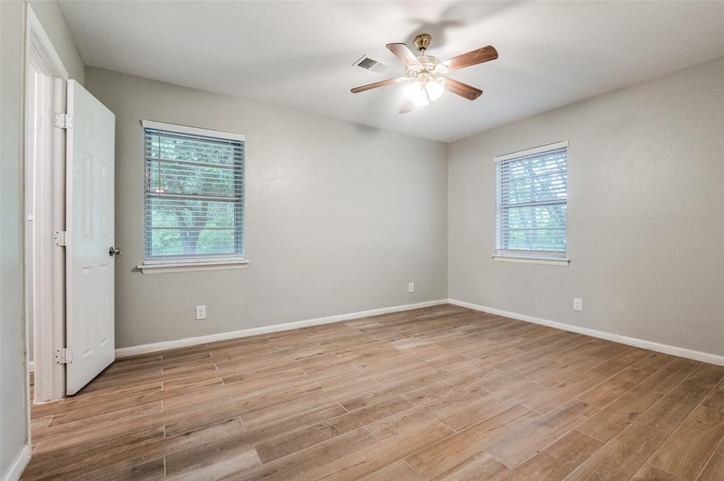 1533 East Springcrest Circle Lancaster, TX 75134 - Photo 19 of 25 Spacious room featuring wood-finish flooring, two large windows with blinds, a ceiling fan with integrated lighting, and neutral wall tones
