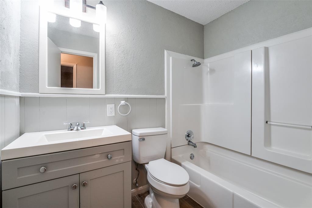 1533 East Springcrest Circle Lancaster, TX 75134 - Photo 22 of 25 Bathroom featuring a gray vanity with an integrated sink, chrome faucet, wall-mounted mirror, and a full bathtub with a shower kit