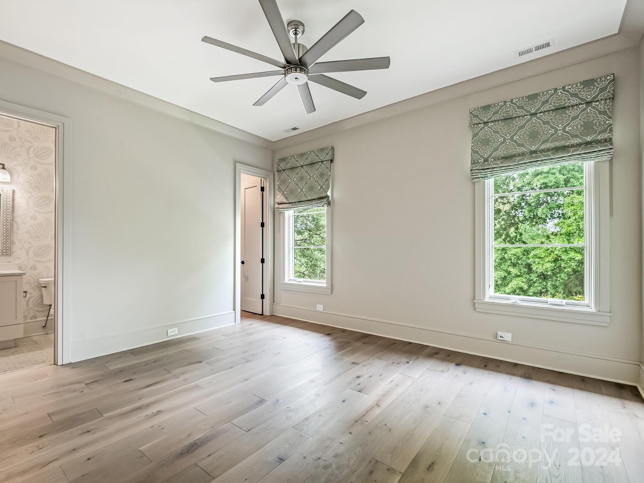 2717 Westfield Road Charlotte, NC 28209 - Photo 23 of 32 an empty room with wooden floor chandelier fan and windows