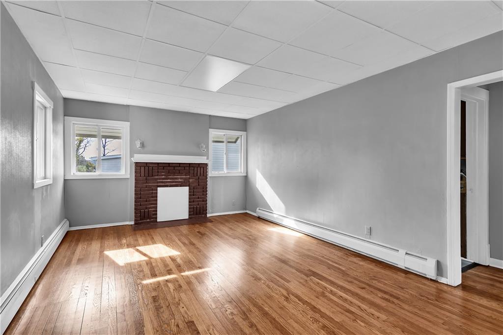 825 Walnut Street Rochester, PA 15074 - Photo 3 of 24 an empty room with wooden floor fireplace and windows