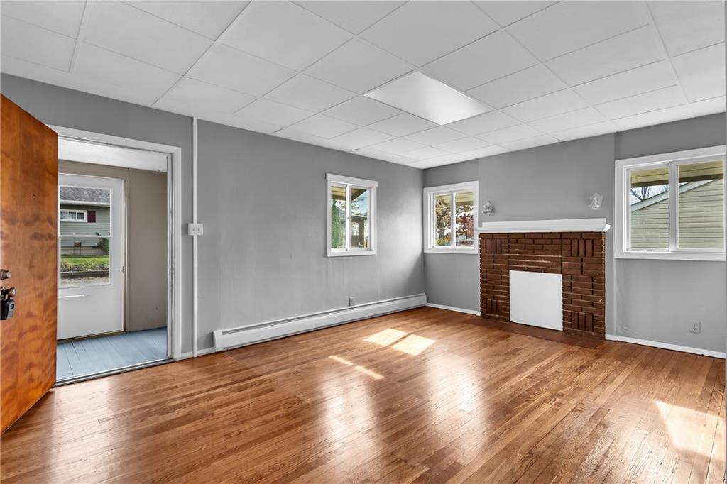 825 Walnut Street Rochester, PA 15074 - Photo 6 of 24 an empty room with wooden floor fireplace and windows