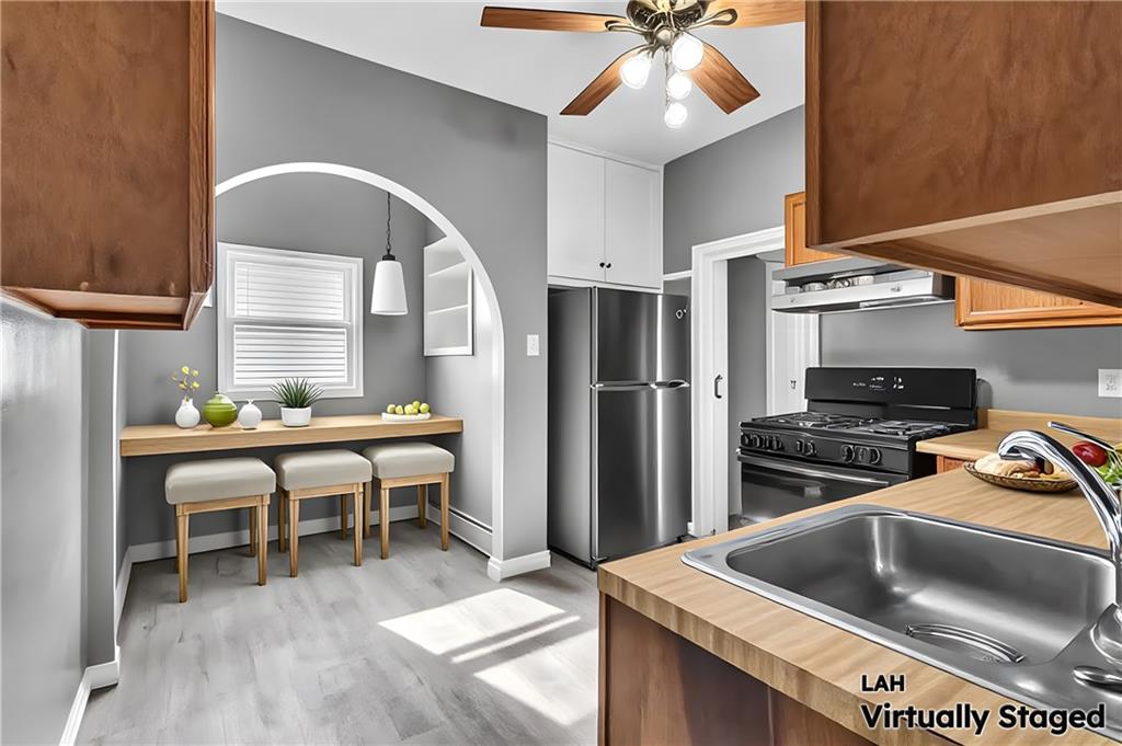 825 Walnut Street Rochester, PA 15074 - Photo 8 of 24 a kitchen with a stove a refrigerator and a dining table with wooden floor