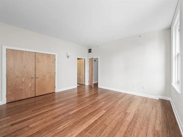 a view of an empty room with wooden floor and closet