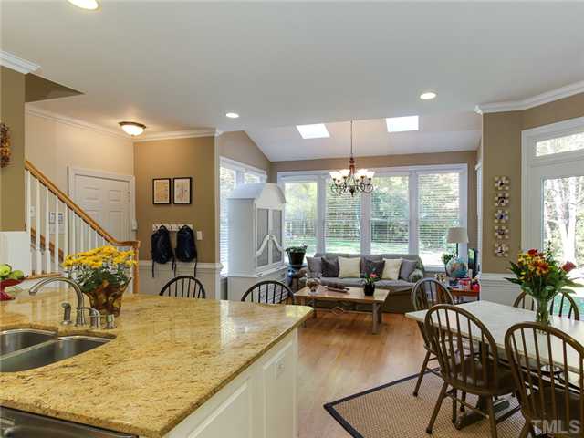 408 Reedham Way Raleigh, NC 27615 - Photo 9 of 25 Kitchen has hardwoods, white cabinetry, granite counter tops, stainless appliances, and room for everyone to gather while entertaining!