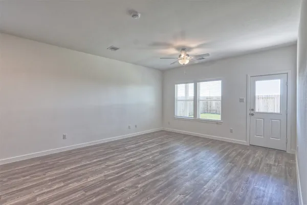 an empty room with wooden floor and windows