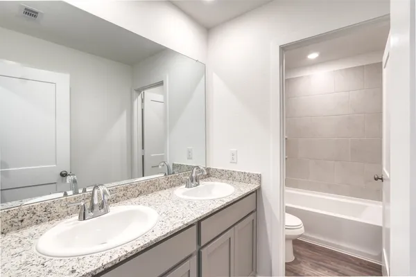 a bathroom with a granite countertop sink a toilet and bathtub