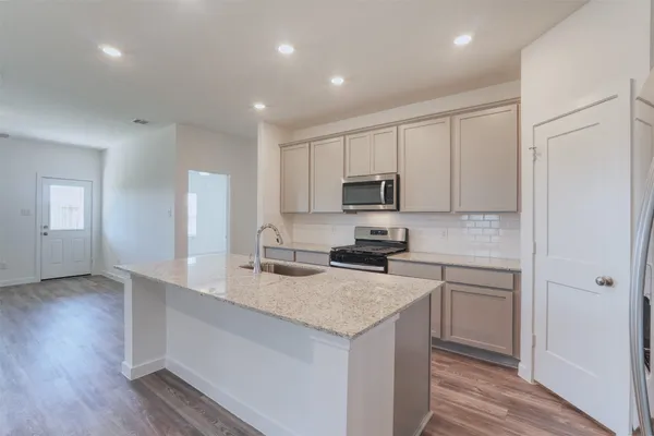 a kitchen with a sink a stove a refrigerator a center island and cabinets