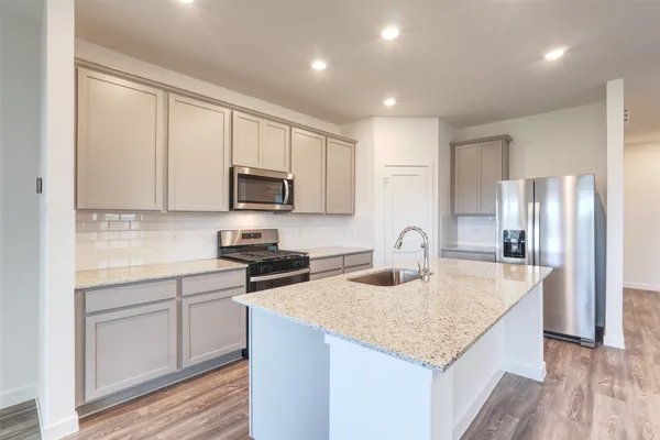 a kitchen with kitchen island granite countertop a stove and a sink