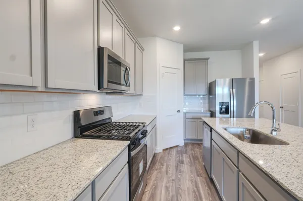a kitchen with a sink stove top oven and refrigerator