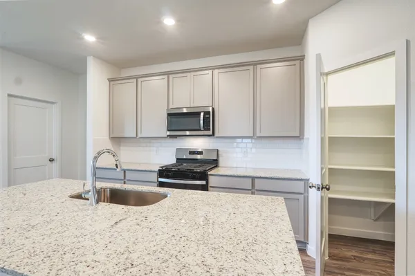 a kitchen with granite countertop a sink stove and cabinets