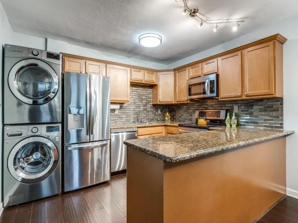 a kitchen with stainless steel appliances granite countertop a sink a stove and a wooden floors