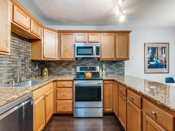 a kitchen with stainless steel appliances granite countertop a stove a sink and a microwave