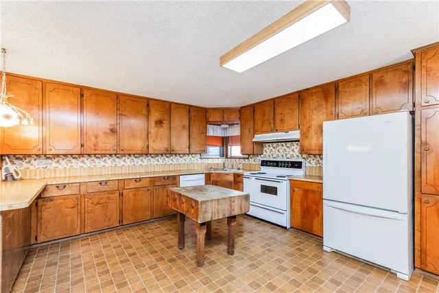 a open kitchen with a sink refrigerator stove dining table and chairs