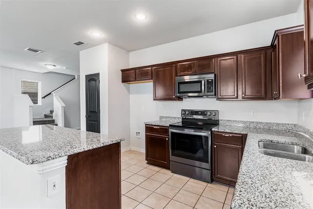 a kitchen with stainless steel appliances granite countertop a kitchen island a stove a sink and a microwave