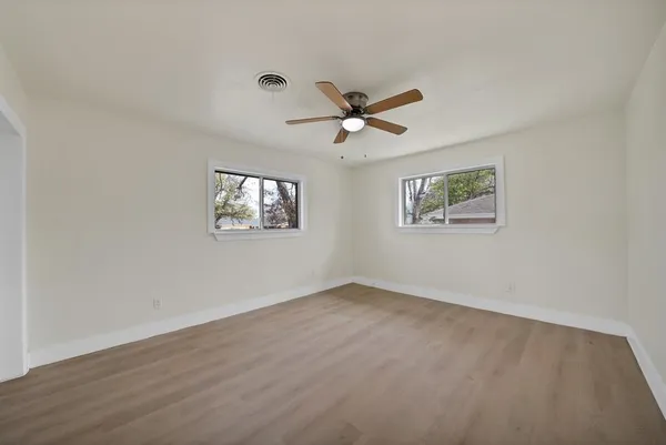 a view of an empty room with a window and a ceiling fan