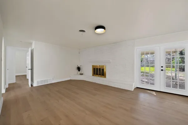 a view of an empty room with window and wooden floor