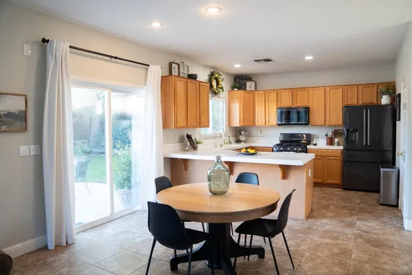 a kitchen with a refrigerator a stove a sink and a dining table with wooden floor
