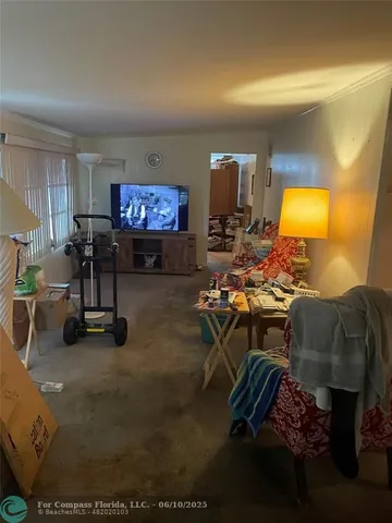 a living room with furniture and a flat screen tv with kitchen view