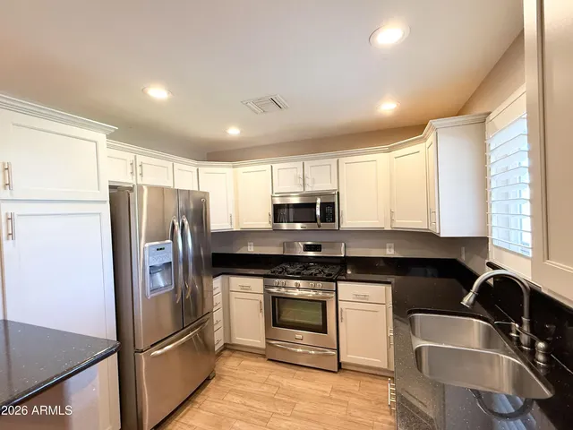 a kitchen with stainless steel appliances granite countertop a stove a refrigerator and a sink