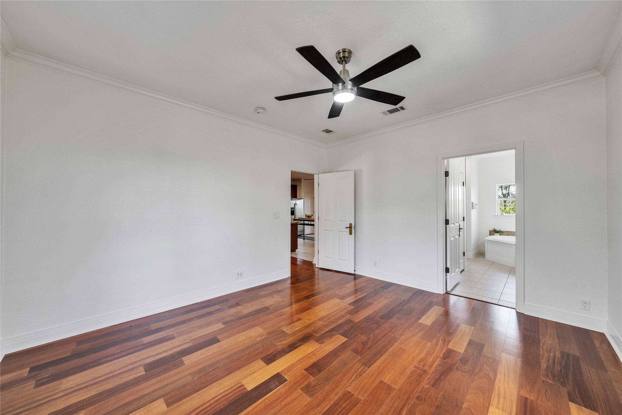 2108 Indian Creek Road Austin, TX 78734 - Photo 14 of 40 Unfurnished bedroom featuring crown molding, ceiling fan, wood finished floors, and ensuite bath