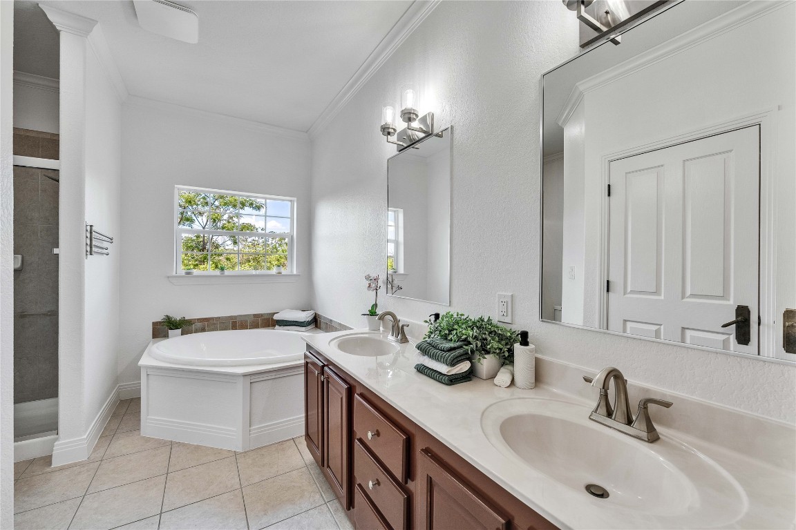 2108 Indian Creek Road Austin, TX 78734 - Photo 15 of 40 Full bathroom featuring a shower stall, a garden tub, double vanity, crown molding, and light tile patterned floors