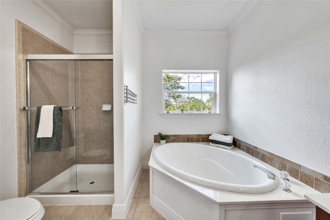 2108 Indian Creek Road Austin, TX 78734 - Photo 16 of 40 Bathroom featuring a shower stall, a garden tub, light tile patterned floors, and ornamental molding