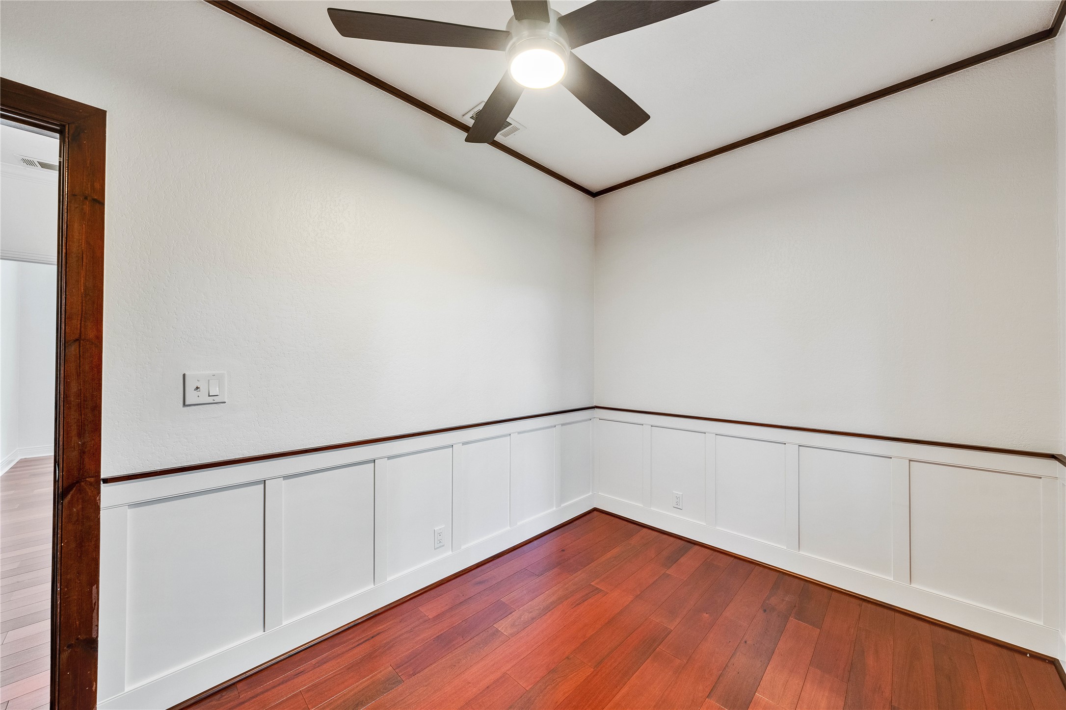2108 Indian Creek Road Austin, TX 78734 - Photo 24 of 40 Unfurnished room with a decorative wall, dark wood-type flooring, crown molding, a wainscoted wall, and a ceiling fan