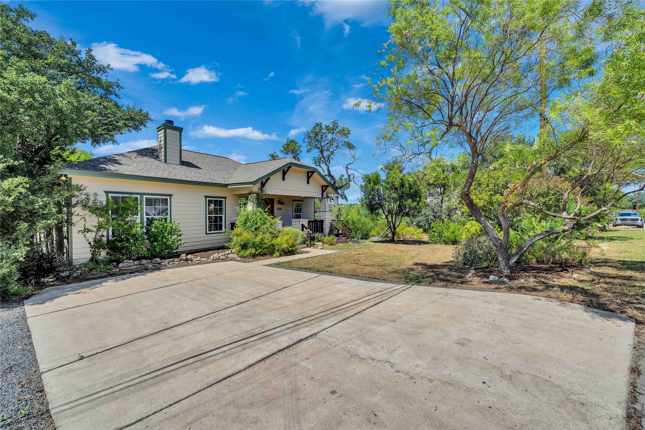 2108 Indian Creek Road Austin, TX 78734 - Photo 28 of 40 Back of property featuring a chimney, a yard, a shingled roof, and covered porch