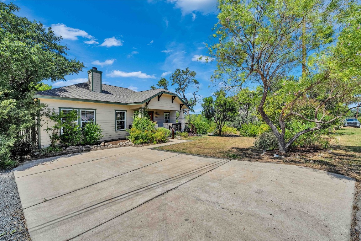 2108 Indian Creek Road Austin, TX 78734 - Photo 28 of 40 Back of property featuring a chimney, a yard, a shingled roof, and covered porch