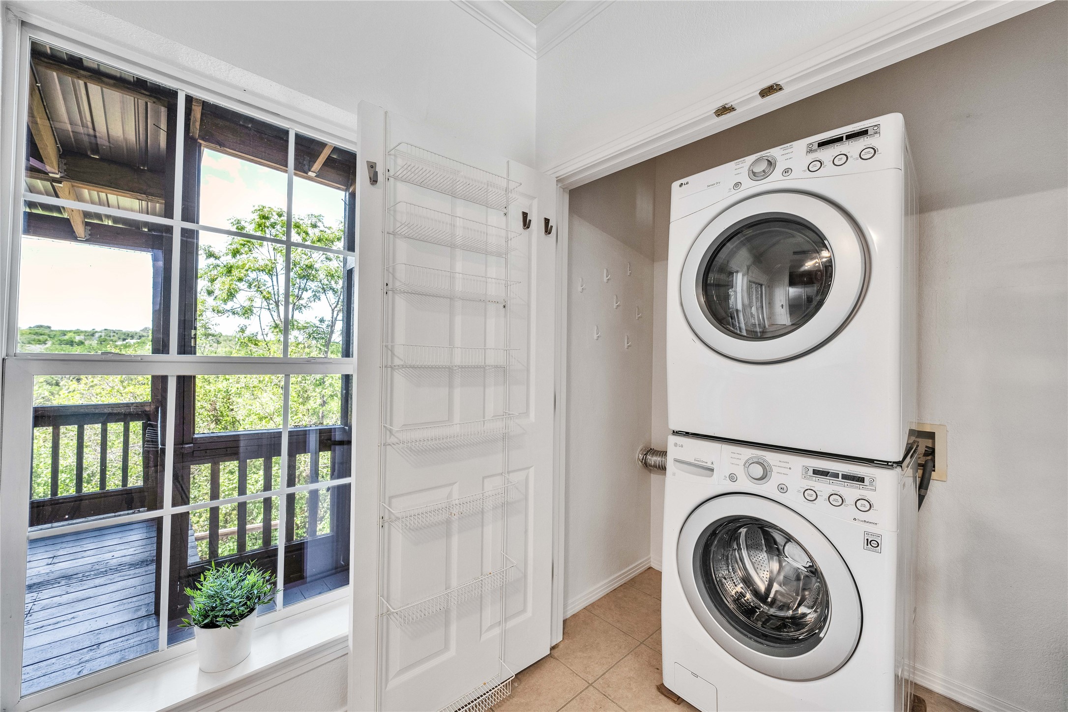 2108 Indian Creek Road Austin, TX 78734 - Photo 33 of 40 Laundry area featuring stacked washing machine and dryer, light tile patterned floors, and crown molding